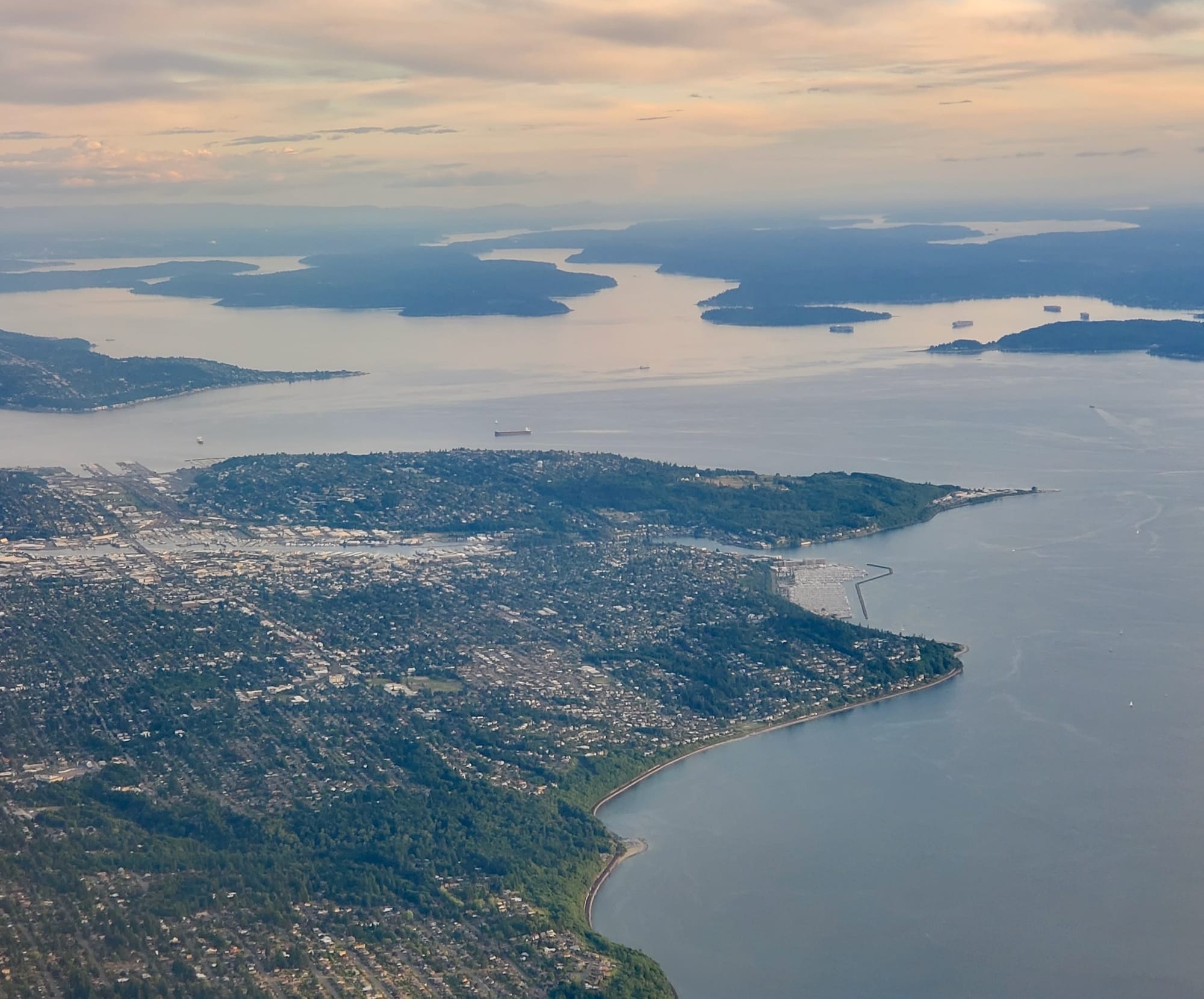 An aerial photo of land filled with dense buildings in some places and surrounded by water.